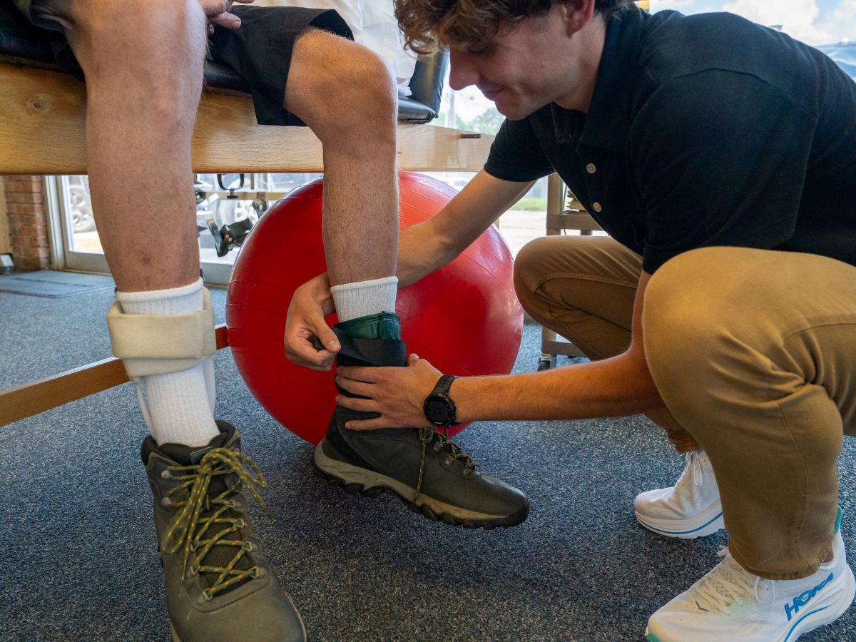 Therapist adjusting ankle weight on senior patient's leg