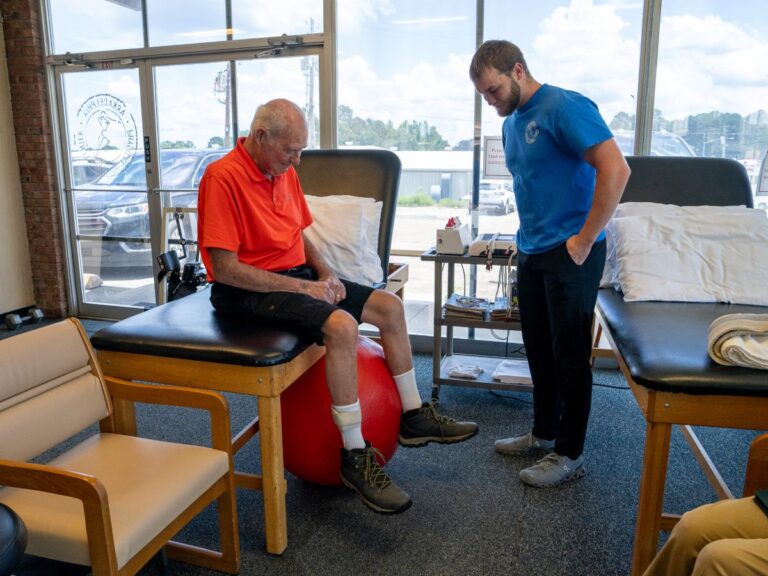 Therapist observing senior man performing seated exercise