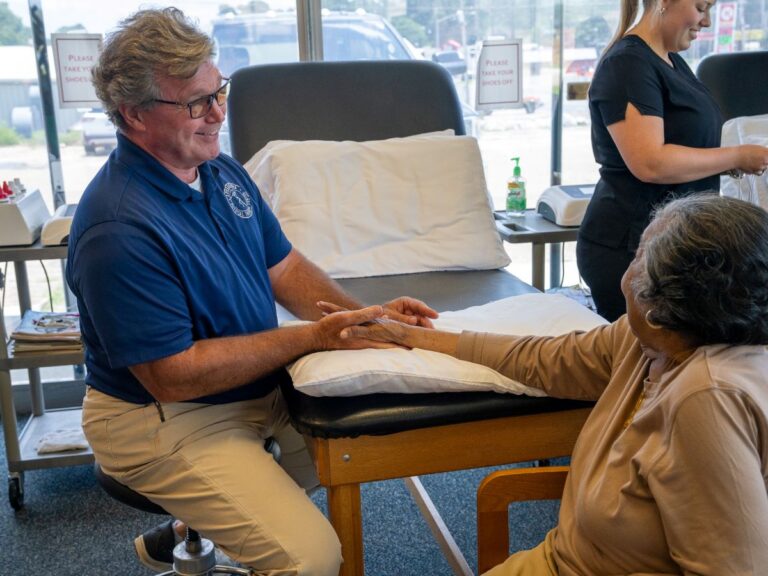 Therapist smiling while treating a senior's hand