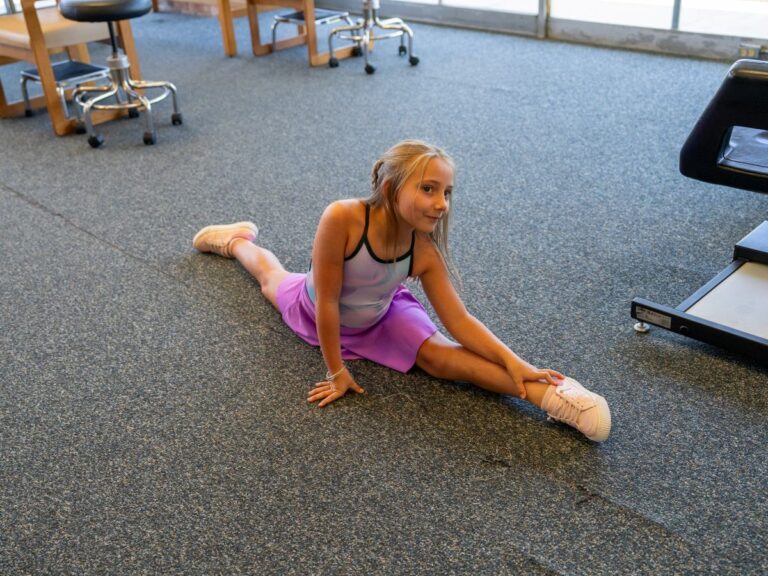 Young girl doing a split stretch exercise in therapy room