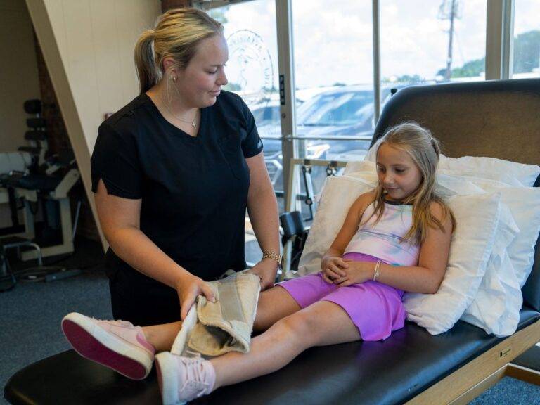 Therapist applying a warm compress to a child's legs during therapy