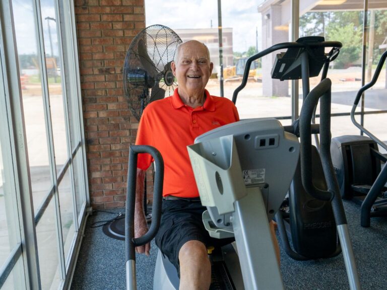 Senior man smiling while using a recumbent bike