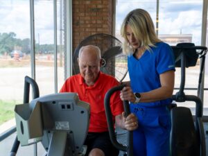 Therapist guiding a senior man on an exercise bike during rehab