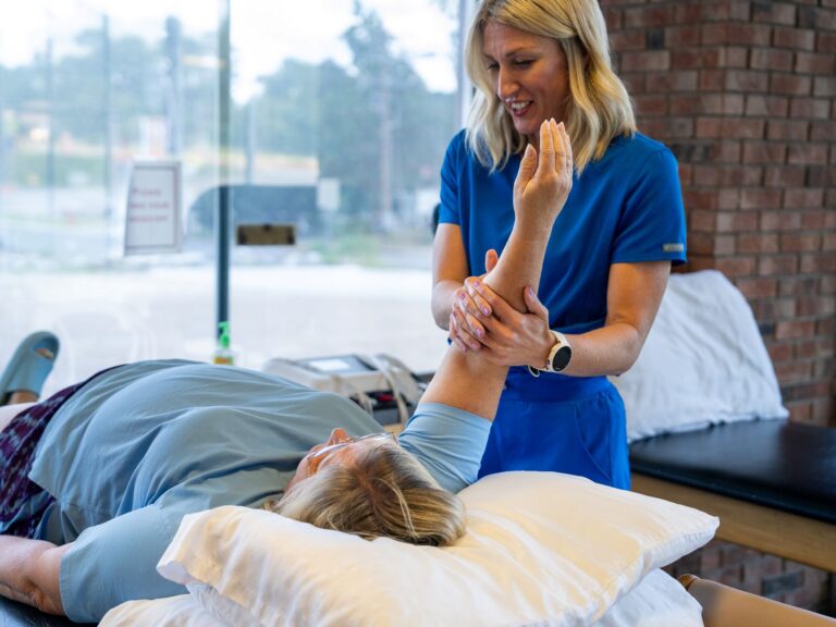 Therapist assisting senior woman with arm rehabilitation at Arkadelphia Physical Therapy Center